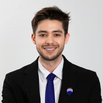 Homme d'affaires souriant portant un costume noir et une cravate bleue.